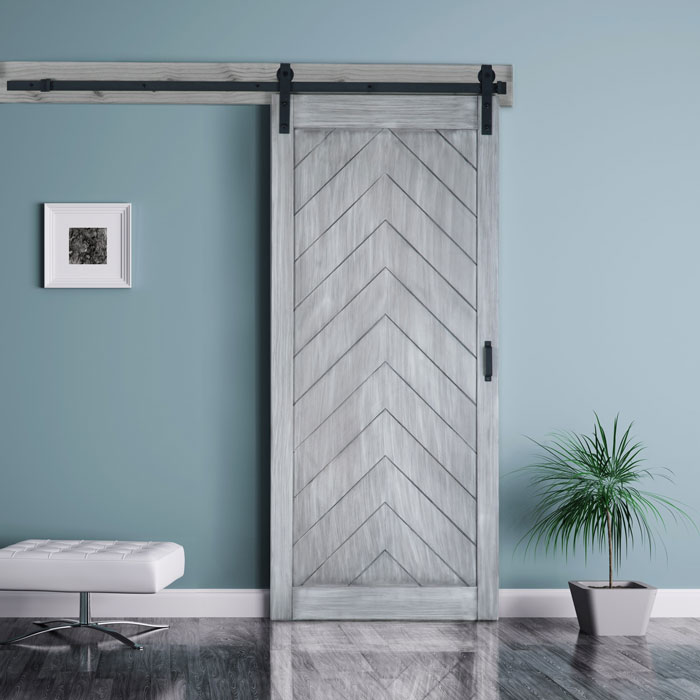 Modern sliding barn door with chevron pattern against a teal wall, accompanied by a white framed artwork and a potted plant, showcasing interior design elements relevant to installation projects by C17media.