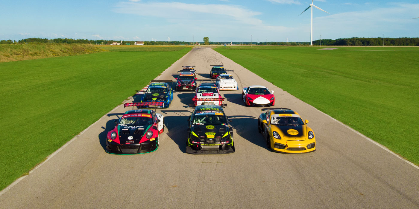 Aerial view of multiple race cars lined up on a track, showcasing vibrant designs and sponsor logos, representing the Canadian Sport Compact Series (CSCS) events supported by C17media.