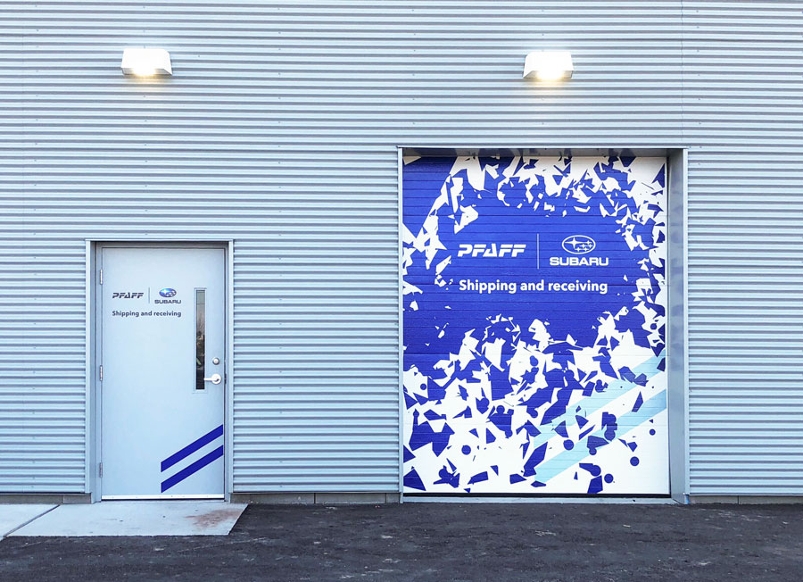 Pfaff Subaru Guelph shipping and receiving door with blue and white graphic design, featuring Subaru and Pfaff logos, enhancing dealership branding.