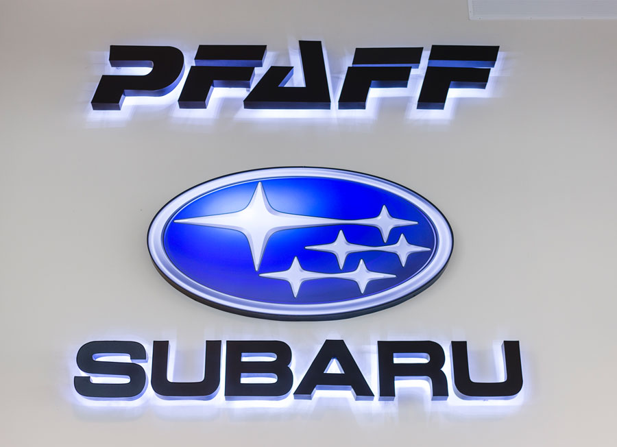 Pfaff Subaru illuminated logo sign with Subaru emblem, enhancing brand visibility in dealership showroom.