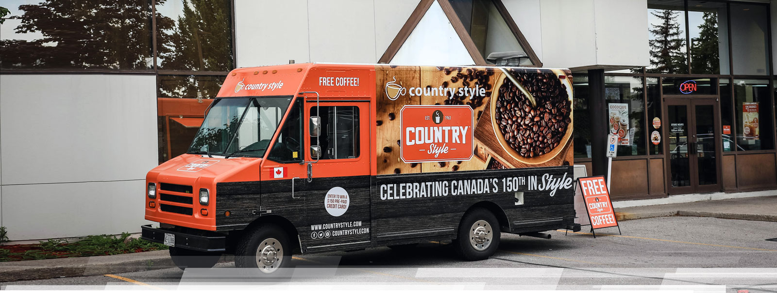 Country Style coffee truck parked outside a storefront, featuring vibrant branding and promotional signage for free coffee and a contest, showcasing large format printing capabilities.