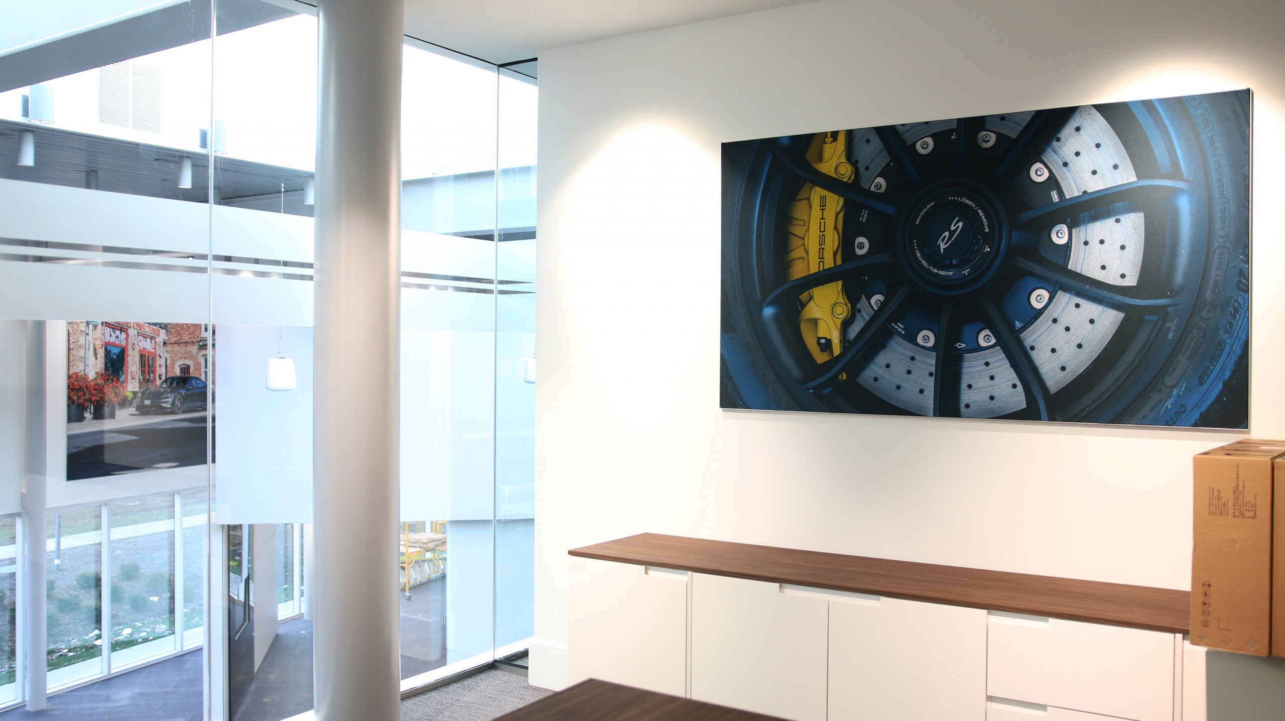 Porsche wheel artwork displayed in modern office setting, emphasizing automotive branding and design aesthetics.