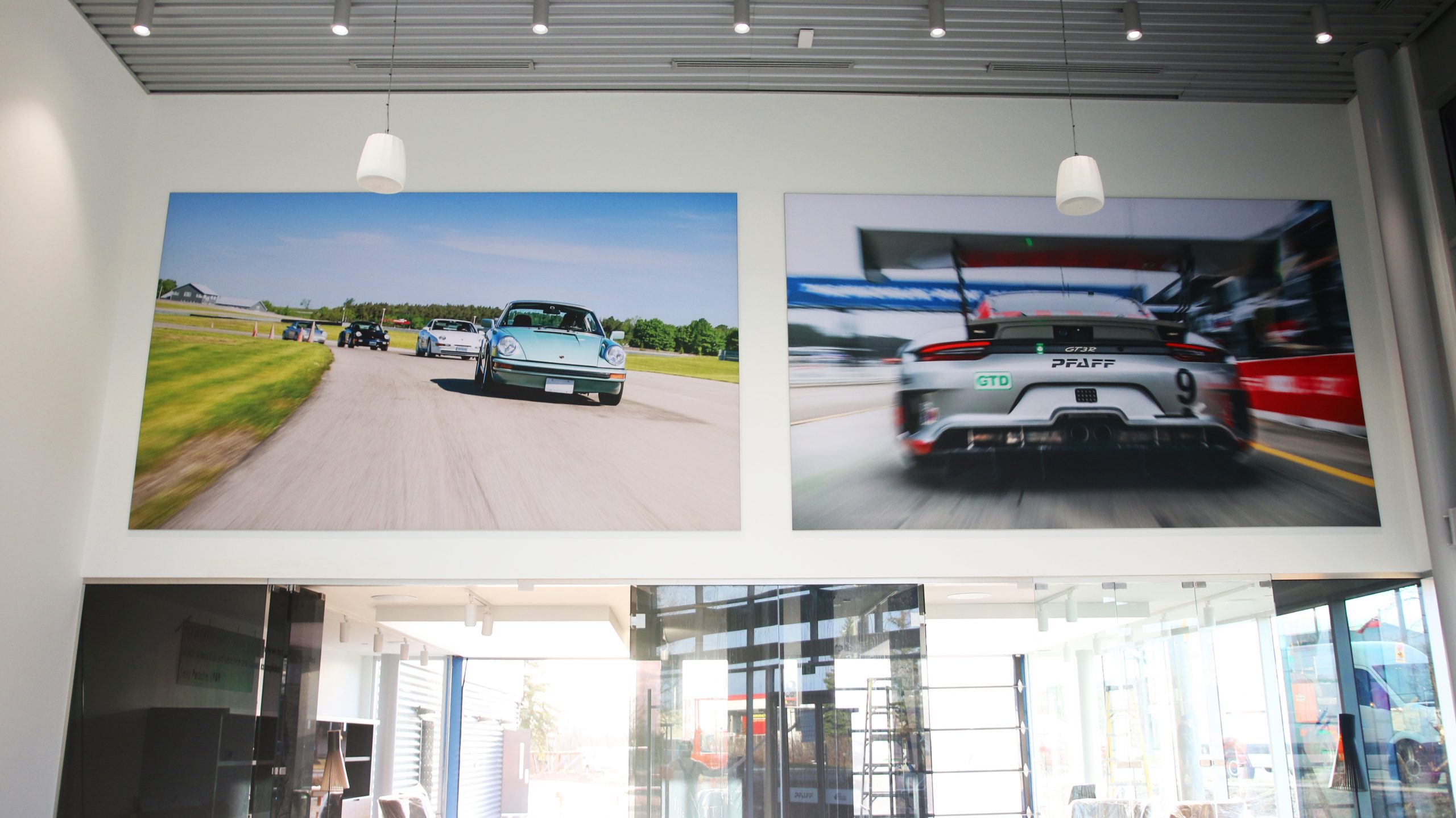 Porsche vehicles in motion displayed on large fabric frames in the showroom of Porsche Centre Markham, enhancing the customer experience and showcasing automotive branding.
