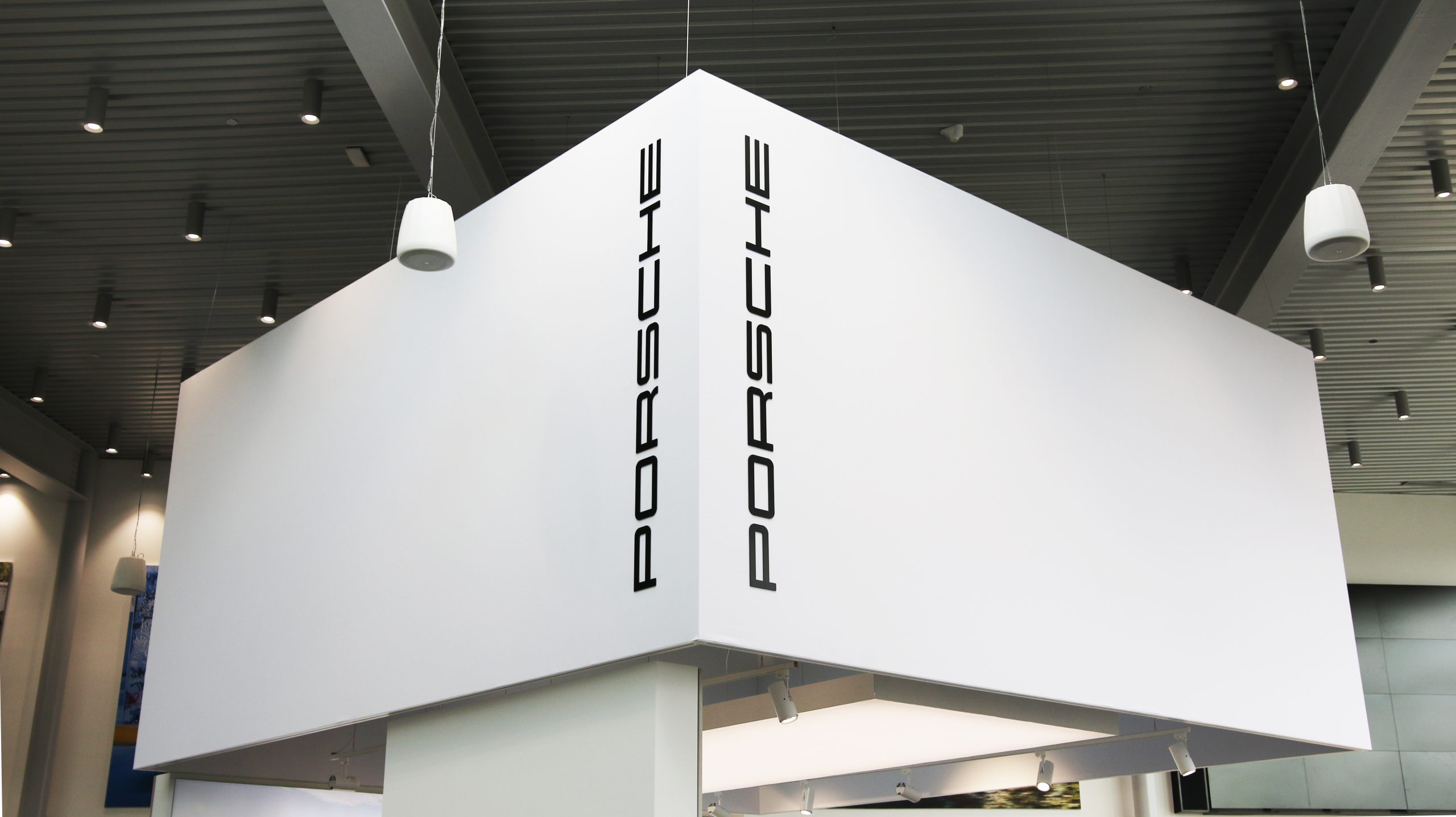 Porsche branding displayed prominently on a showroom bulkhead, featuring sleek black letters against a white background, enhancing the visual impact of the Porsche Centre Markham's interior design.